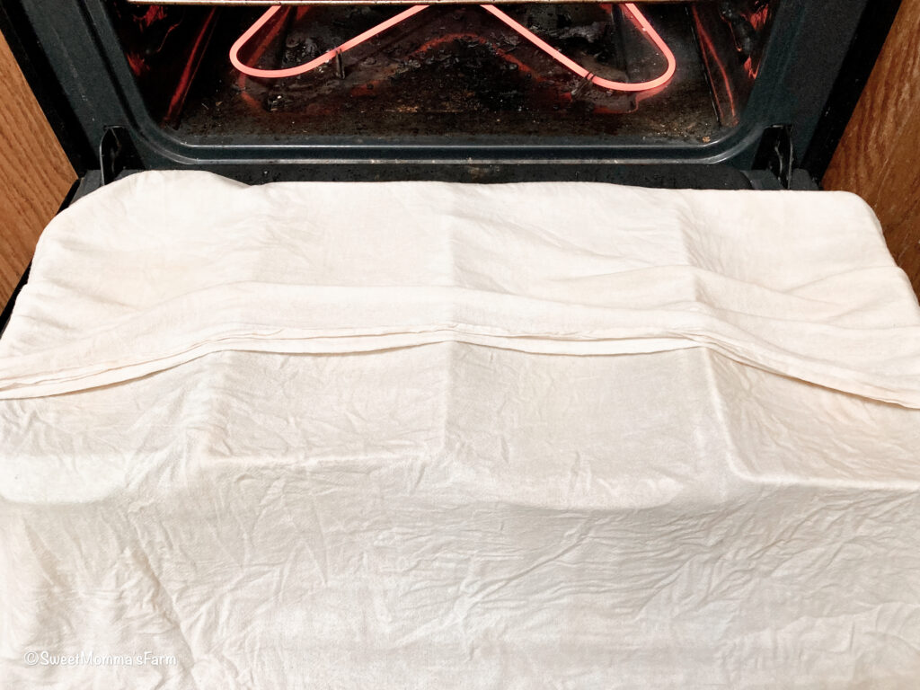 Four pan loaves covered with a damp cheesecloth
