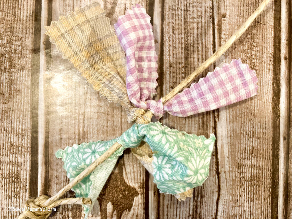 Strip of green, yellow and purple fabric tied on to jute string