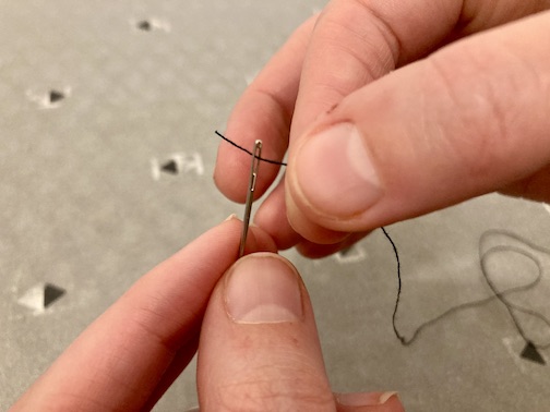 Fingers threading a needle