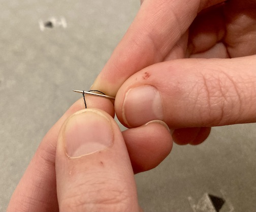 The first weave in marrying the needle and thread by weaving the needle into the thread.