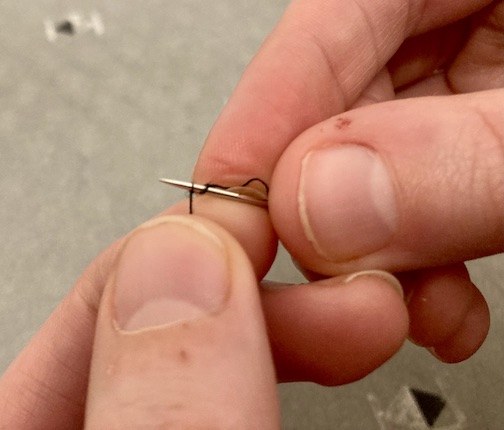 Second weave to marrying the needle and thread by weaving the needle into the thread.