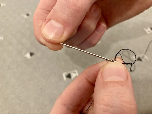 Pulling the three weaves of thread down to the end of the needle