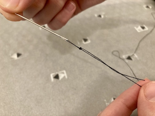 Pulling the three weaves of thread down to the end of the needle