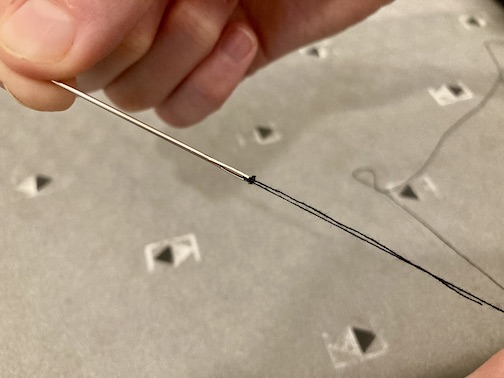 Pulling the three weaves of thread down to the end of the needle