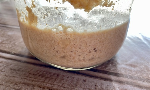 Natural Yeast is placed in a larger glass container with more bubbles forming