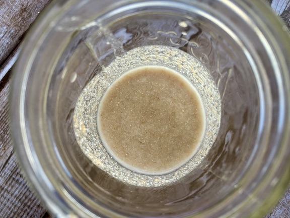 water, flour and wheat berries mixed together in a glass jar