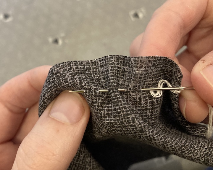 A needle attached to thread weaved through the fabric
