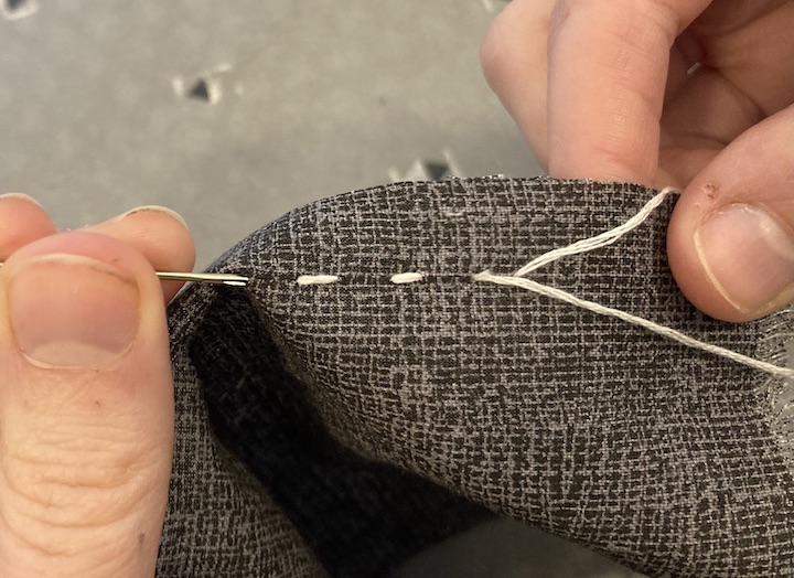 After weaving through the fabric the needle is being pulled causing the thread to go through the fabric