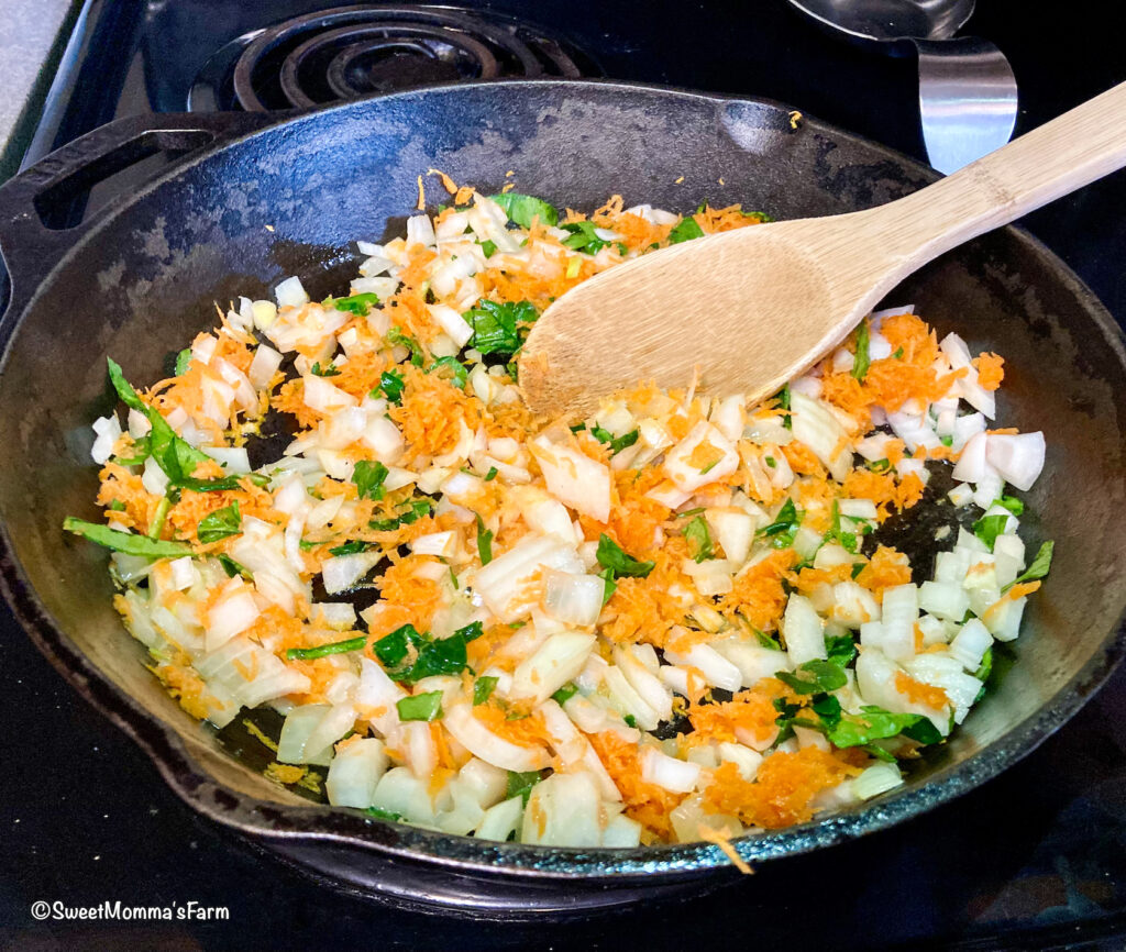 Shredded carrots, chopped onion and spinach sauteing in a pan