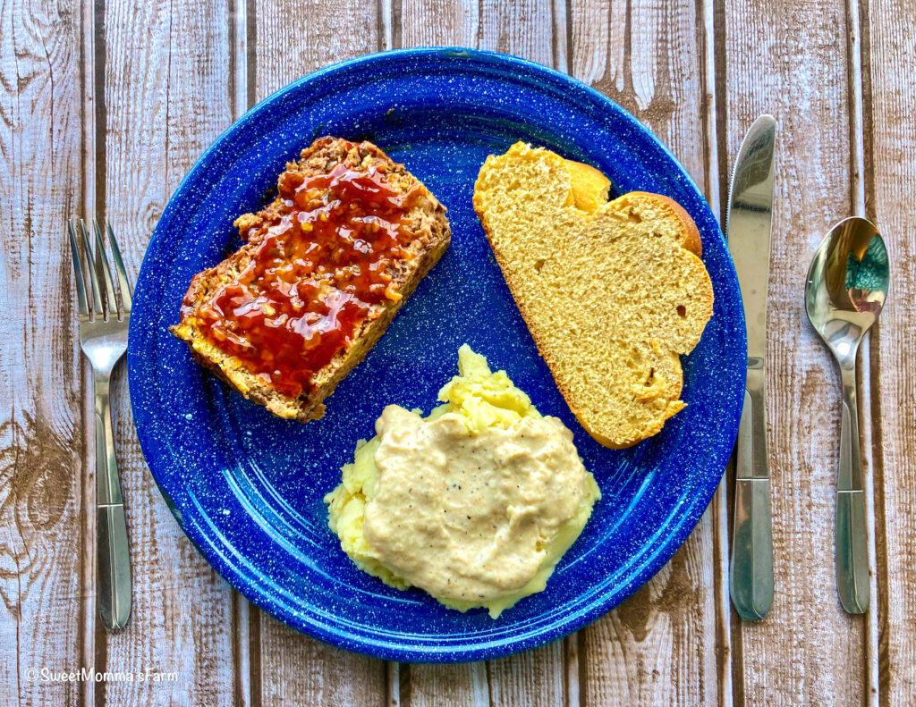 Veggie-Packed Meatloaf with Garlic and Honey sauce on a dinner plate with a slice of bread and mashed potatoes